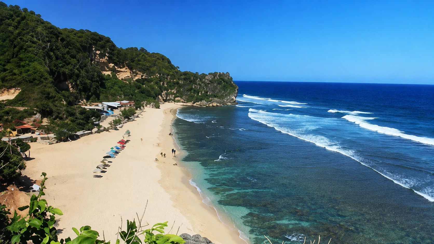 Pantai Pok Tunggal dengan pasir putih, laut biru, dan perbukitan karang